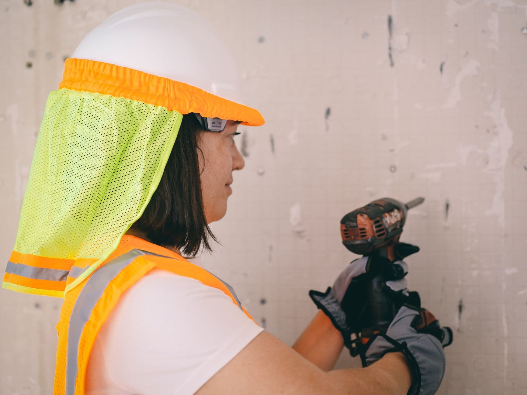 A technician in safety gear drilling into a wall