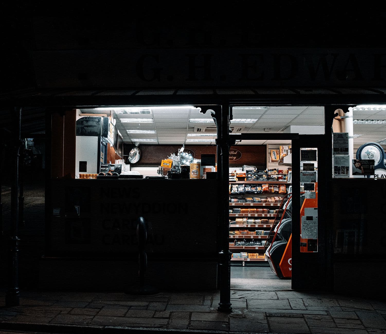 A shop lit up at night on a dark street