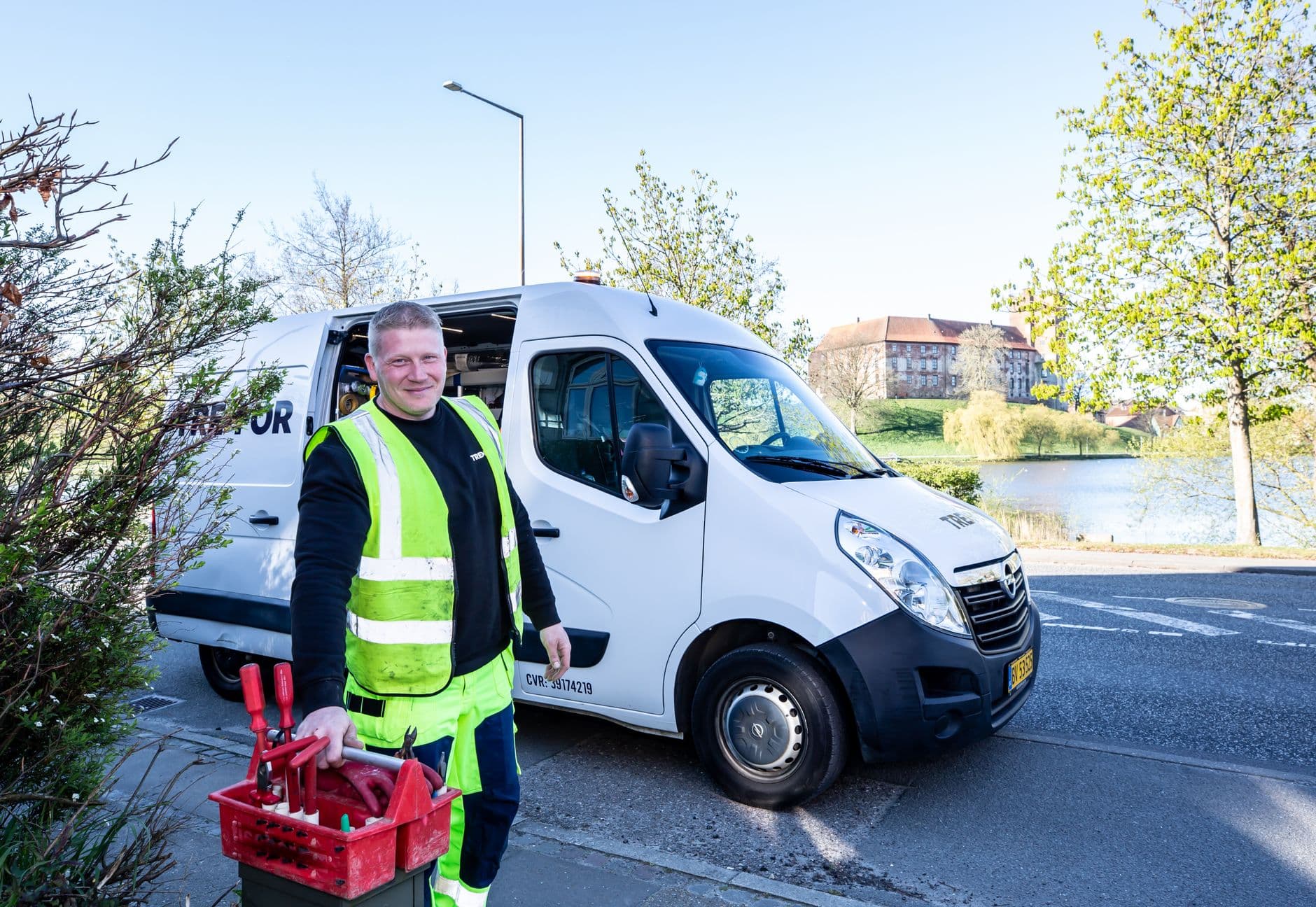 A technician with a toolbox standing beside a work van